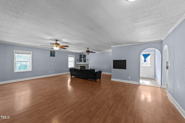 282 Cooke Rd, Louisburg, NC 27549 - unfurnished living room featuring a textured ceiling, a ceiling fan, a fireplace, arched walkways, and healthy amount of natural light