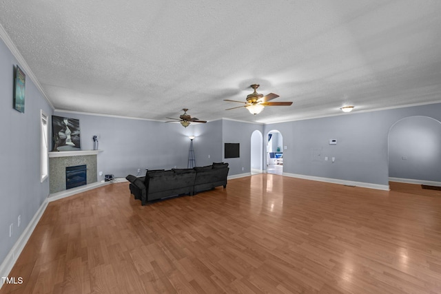 282 Cooke Rd, Louisburg, NC 27549 - unfurnished living room featuring arched walkways, ornamental molding, wood finished floors, ceiling fan, and a fireplace