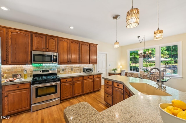 6829 Wood Forest Dr, Cary, NC 27519 - kitchen featuring appliances with stainless steel finishes, a chandelier, decorative light fixtures, light wood-style floors, and tasteful backsplash