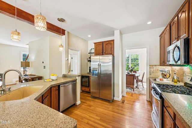 6829 Wood Forest Dr, Cary, NC 27519 - kitchen with stainless steel appliances, light wood-style flooring, decorative light fixtures, backsplash, and recessed lighting