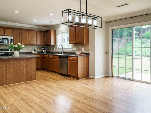 1833 Creek Oak Cir, Fuquay Varina, NC 27526 - kitchen with appliances with stainless steel finishes, ornamental molding, light wood-style floors, dark countertops, and a sink