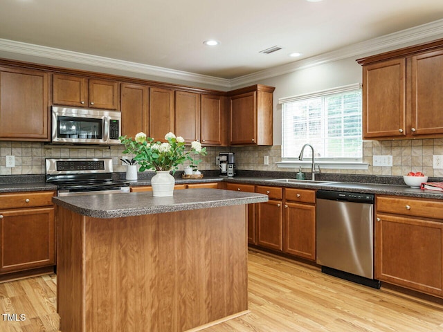 1833 Creek Oak Cir, Fuquay Varina, NC 27526 - kitchen featuring stainless steel appliances, a sink, a kitchen island, crown molding, and light wood-style flooring