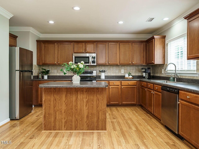 1833 Creek Oak Cir, Fuquay Varina, NC 27526 - kitchen with stainless steel appliances, a sink, light wood-style flooring, crown molding, and dark countertops