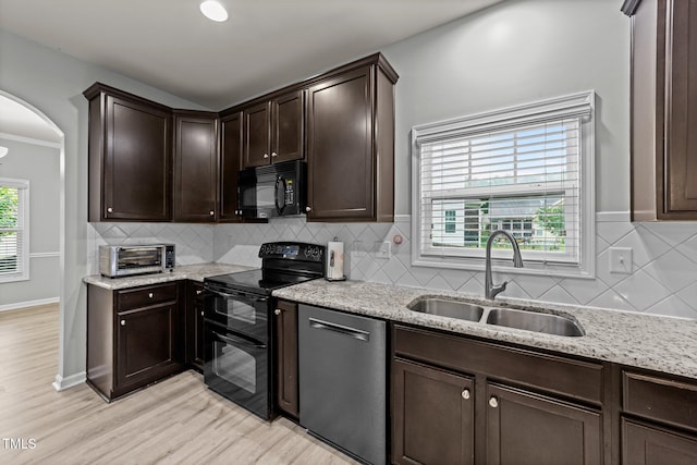 2709 Banks Lake Ct, Fuquay Varina, NC 27526 - kitchen featuring black appliances, a sink, arched walkways, dark brown cabinetry, and light stone countertops
