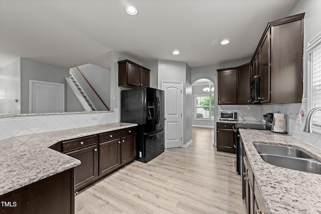 2709 Banks Lake Ct, Fuquay Varina, NC 27526 - kitchen with black appliances, a sink, light wood finished floors, dark brown cabinetry, and decorative backsplash