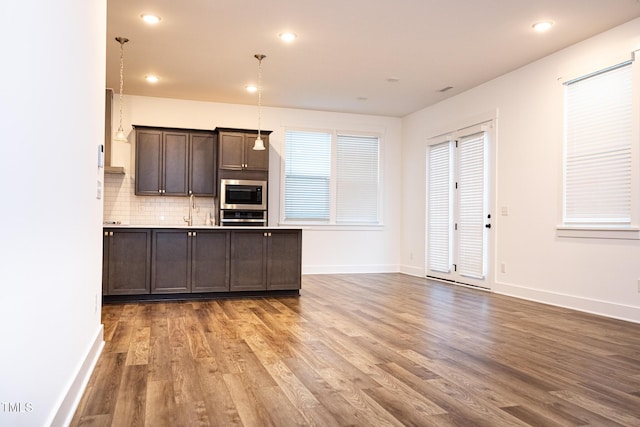 1950 Menet St, Apex, NC 27502 - kitchen featuring appliances with stainless steel finishes, wood finished floors, dark brown cabinetry, decorative backsplash, and baseboards