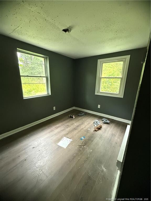 209 Rose St, Spring Lake, NC 28390 - unfurnished bedroom featuring multiple windows, baseboards, wood finished floors, and a textured ceiling