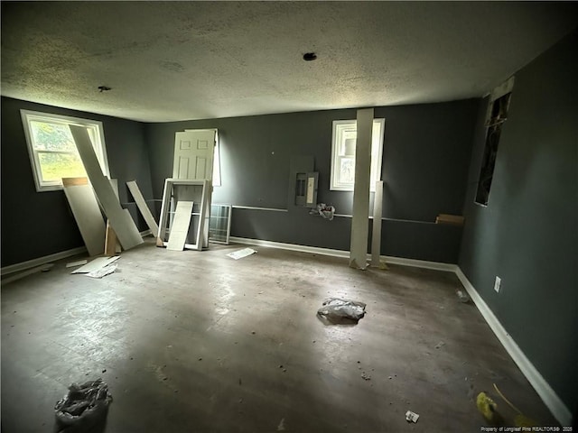 209 Rose St, Spring Lake, NC 28390 - empty room featuring a textured ceiling, baseboards, unfinished concrete flooring, and electric panel