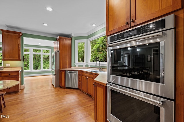 1501 Chatsworth Ln, Raleigh, NC 27614 - kitchen featuring appliances with stainless steel finishes, a sink, crown molding, light wood-style floors, and brown cabinets