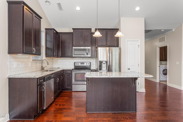 4110 Argyle Trl, Burlington, NC 27215 - kitchen with appliances with stainless steel finishes, washer / dryer, a sink, a kitchen island, and dark brown cabinets