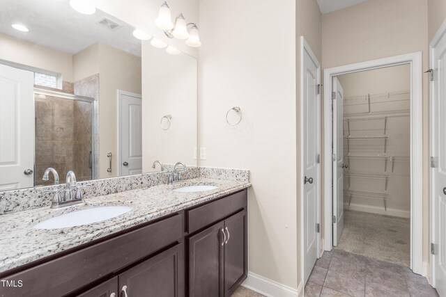 4110 Argyle Trl, Burlington, NC 27215 - bathroom featuring a stall shower, double vanity, a spacious closet, and tile patterned floors