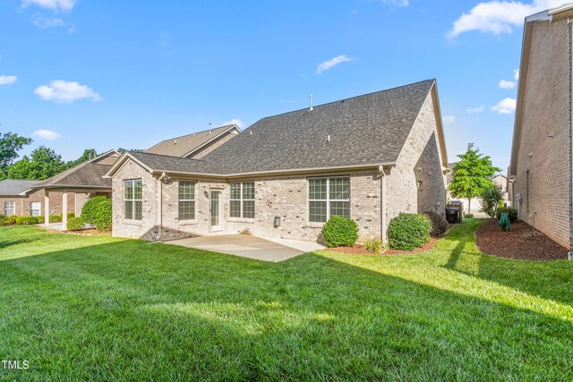 4110 Argyle Trl, Burlington, NC 27215 - back of house with a patio area, brick siding, roof with shingles, and a lawn