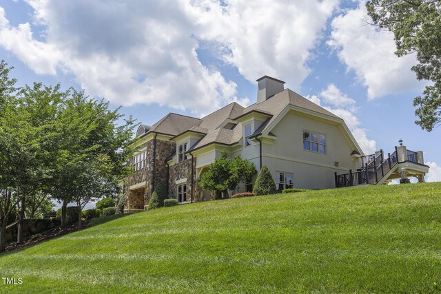 4110 Argyle Trl, Burlington, NC 27215 - view of side of home featuring a lawn, stone siding, a chimney, and stucco siding