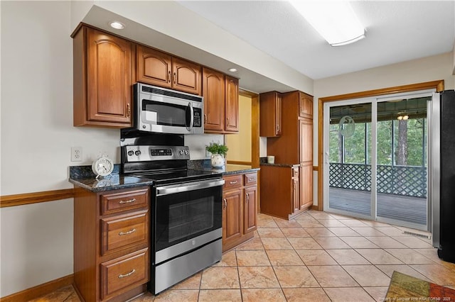 38 E Lndg, Sanford, NC 27332 - kitchen featuring stainless steel appliances, brown cabinetry, dark stone counters, baseboards, and light tile patterned flooring