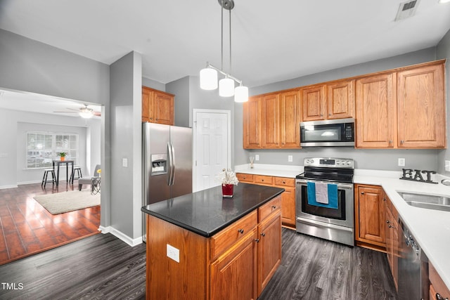 10941 Pendragon Pl, Raleigh, NC 27614 - kitchen featuring appliances with stainless steel finishes, dark wood-style flooring, a sink, a center island, and hanging light fixtures