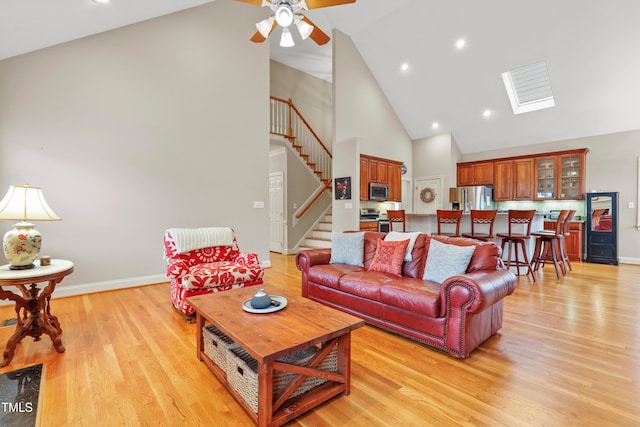 327 Commons Walk Cir, Cary, NC 27519 - living area with high vaulted ceiling, stairway, baseboards, ceiling fan, and light wood-style floors
