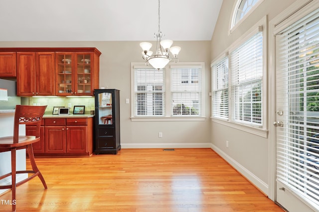 327 Commons Walk Cir, Cary, NC 27519 - kitchen with a chandelier, light wood-type flooring, lofted ceiling, decorative light fixtures, and glass insert cabinets