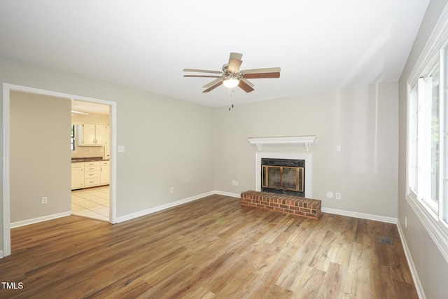 2012 Stadium Dr, Durham, NC 27705 - unfurnished living room featuring light wood finished floors, a ceiling fan, a brick fireplace, and plenty of natural light