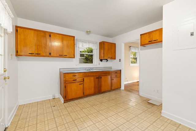 2015 Walnut St, Durham, NC 27705 - kitchen featuring brown cabinetry, electric panel, light countertops, baseboards, and healthy amount of natural light