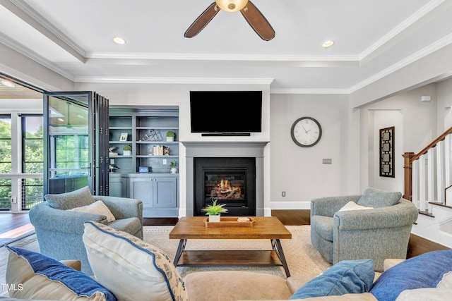 1716 Arberdour Dr, Apex, NC 27502 - living room with stairway, a glass covered fireplace, wood finished floors, a ceiling fan, and ornamental molding