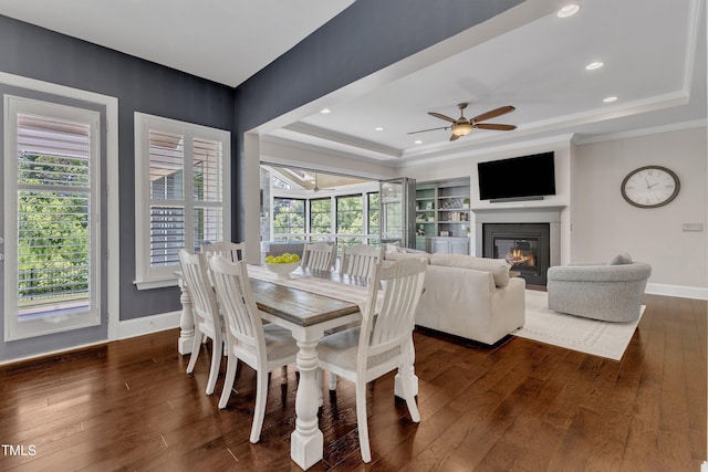 1716 Arberdour Dr, Apex, NC 27502 - dining room featuring baseboards, a tray ceiling, dark wood finished floors, a glass covered fireplace, and a ceiling fan