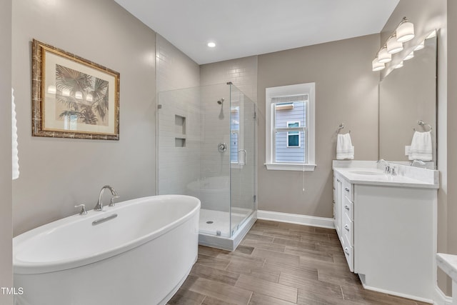 1716 Arberdour Dr, Apex, NC 27502 - bathroom with vanity, a stall shower, a soaking tub, wood finished floors, and recessed lighting
