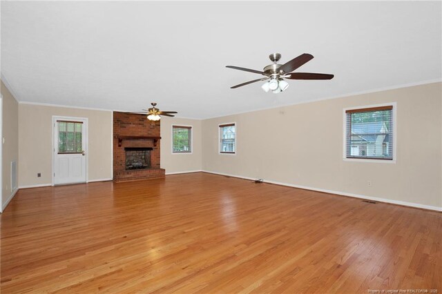 687 Blawell St, Stedman, NC 28391 - unfurnished living room featuring ceiling fan, light wood-style floors, healthy amount of natural light, a brick fireplace, and ornamental molding