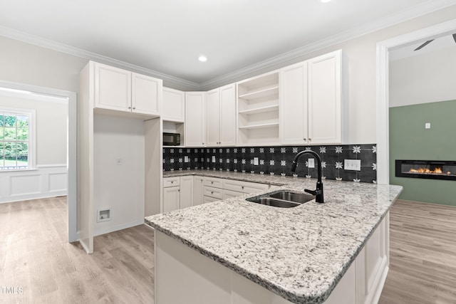 2015 Saddlebrook Dr, Archer Lodge, NC 27527 - kitchen featuring open shelves, a sink, a peninsula, light stone countertops, and crown molding