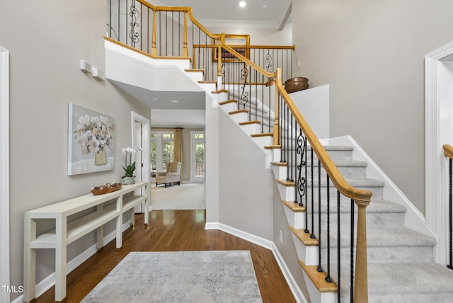 704 Walcott Way, Cary, NC 27519 - stairway featuring wood finished floors, baseboards, a high ceiling, and ornamental molding