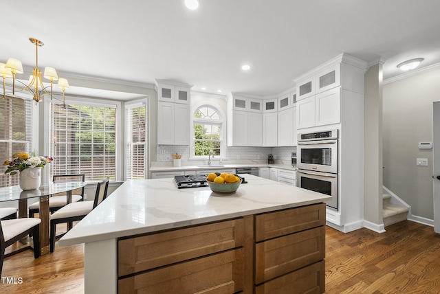 704 Walcott Way, Cary, NC 27519 - kitchen featuring stainless steel appliances, crown molding, a sink, a chandelier, and wood finished floors