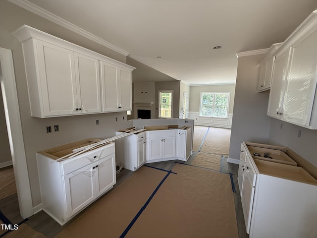 2744 Rains Mill Rd, Princeton, NC 27569 - kitchen with a peninsula, white cabinetry, a large fireplace, baseboards, and crown molding