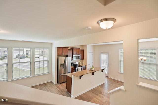 72 S Grey Abbey Dr, Clayton, NC 27527 - kitchen featuring appliances with stainless steel finishes, a kitchen bar, light wood finished floors, a kitchen island, and baseboards