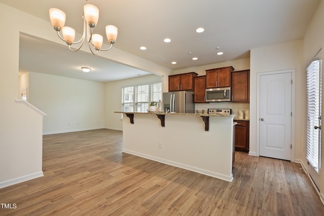 72 S Grey Abbey Dr, Clayton, NC 27527 - kitchen with stainless steel appliances, a breakfast bar, light wood finished floors, light stone counters, and recessed lighting