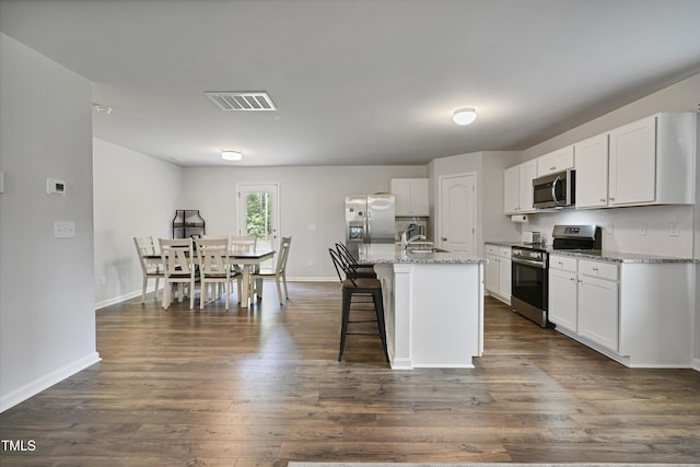 124 Teagarden Ct, Sanford, NC 27332 - kitchen featuring appliances with stainless steel finishes, white cabinets, a kitchen breakfast bar, a kitchen island with sink, and light stone countertops