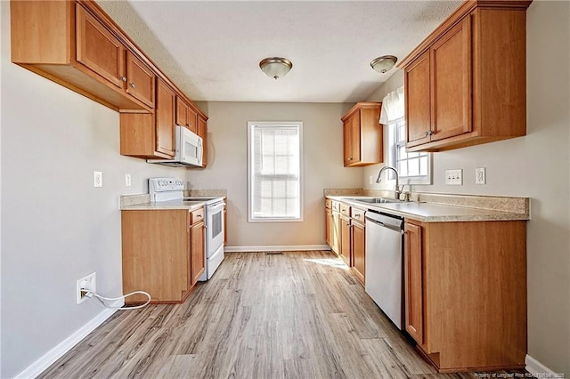 1414 Seabiscuit Dr, Parkton, NC 28371 - kitchen with white appliances, a sink, light wood-style flooring, and baseboards
