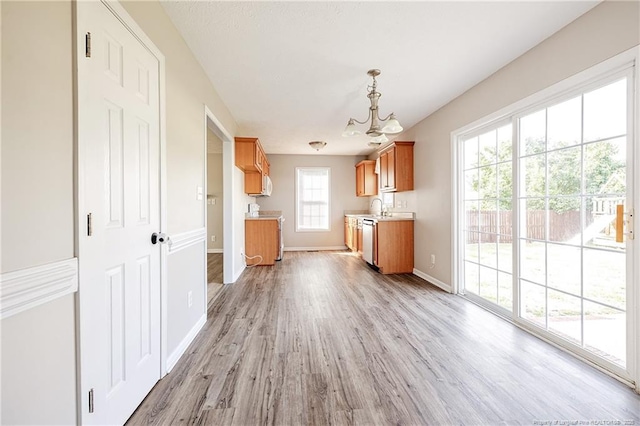 1414 Seabiscuit Dr, Parkton, NC 28371 - kitchen with a chandelier, brown cabinetry, light countertops, light wood-type flooring, and dishwasher