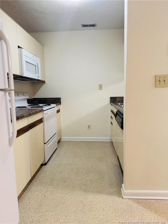 661 Bartons Landing Pl Unit 9, Fayetteville, NC 28314 - kitchen featuring white appliances, white cabinetry, dark countertops, baseboards, and light carpet