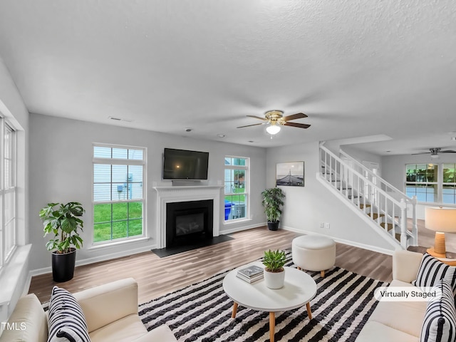 1216 Briarwood Dr, Mebane, NC 27302 - living area featuring ceiling fan, wood finished floors, stairway, a fireplace with flush hearth, and baseboards