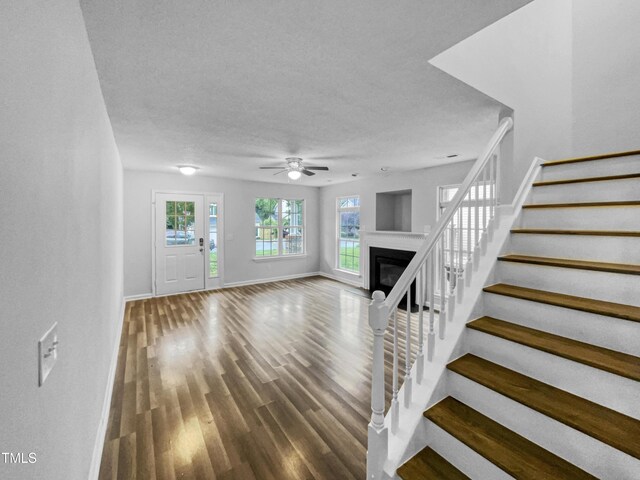 1216 Briarwood Dr, Mebane, NC 27302 - unfurnished living room with stairway, baseboards, a ceiling fan, a glass covered fireplace, and wood finished floors