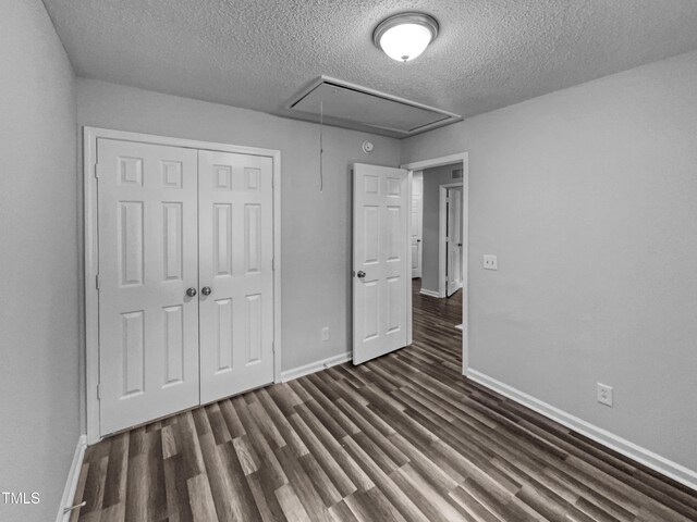 1216 Briarwood Dr, Mebane, NC 27302 - unfurnished bedroom with attic access, a textured ceiling, dark wood finished floors, baseboards, and a closet