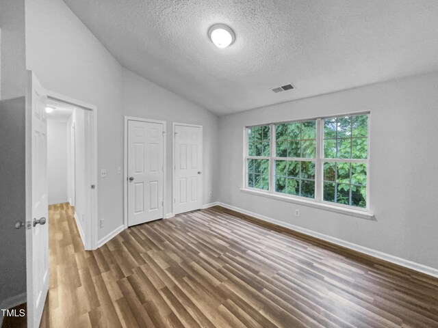 1216 Briarwood Dr, Mebane, NC 27302 - unfurnished bedroom with wood finished floors, lofted ceiling, a textured ceiling, and baseboards