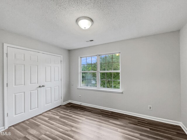 1216 Briarwood Dr, Mebane, NC 27302 - unfurnished bedroom featuring wood finished floors, baseboards, a textured ceiling, and a closet