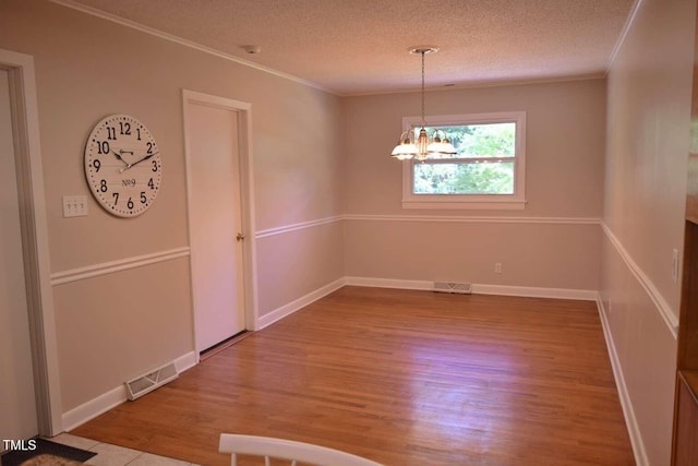 515 Wildwood Dr, Durham, NC 27712 - unfurnished dining area featuring wood finished floors, ornamental molding, a chandelier, a textured ceiling, and baseboards