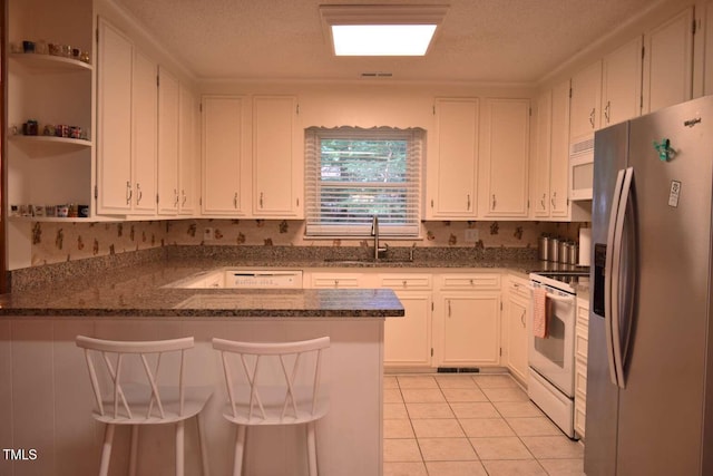 515 Wildwood Dr, Durham, NC 27712 - kitchen featuring white appliances, a sink, a peninsula, and white cabinetry