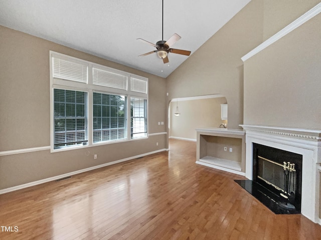 1005 Augustine Trl, Cary, NC 27518 - unfurnished living room featuring a ceiling fan, arched walkways, wood finished floors, high vaulted ceiling, and a fireplace with flush hearth