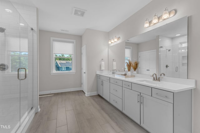 109 Crested Coral Dr, Holly Springs, NC 27540 - bathroom featuring healthy amount of natural light, double vanity, a shower stall, and wood finished floors