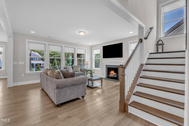 109 Crested Coral Dr, Holly Springs, NC 27540 - living room featuring a fireplace with flush hearth, stairway, baseboards, light wood finished floors, and recessed lighting