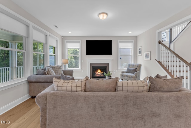 109 Crested Coral Dr, Holly Springs, NC 27540 - living area featuring light wood-style floors, baseboards, a glass covered fireplace, recessed lighting, and stairs