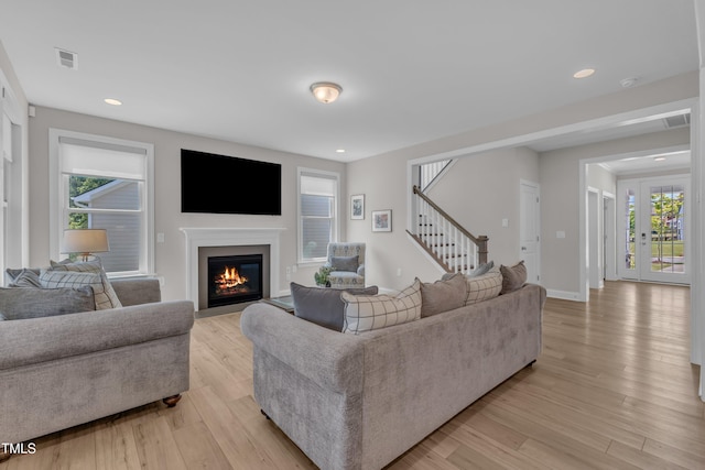 109 Crested Coral Dr, Holly Springs, NC 27540 - living room with stairway, healthy amount of natural light, light wood finished floors, a glass covered fireplace, and recessed lighting
