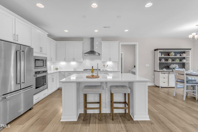 109 Crested Coral Dr, Holly Springs, NC 27540 - kitchen with appliances with stainless steel finishes, wall chimney exhaust hood, light countertops, white cabinetry, and recessed lighting
